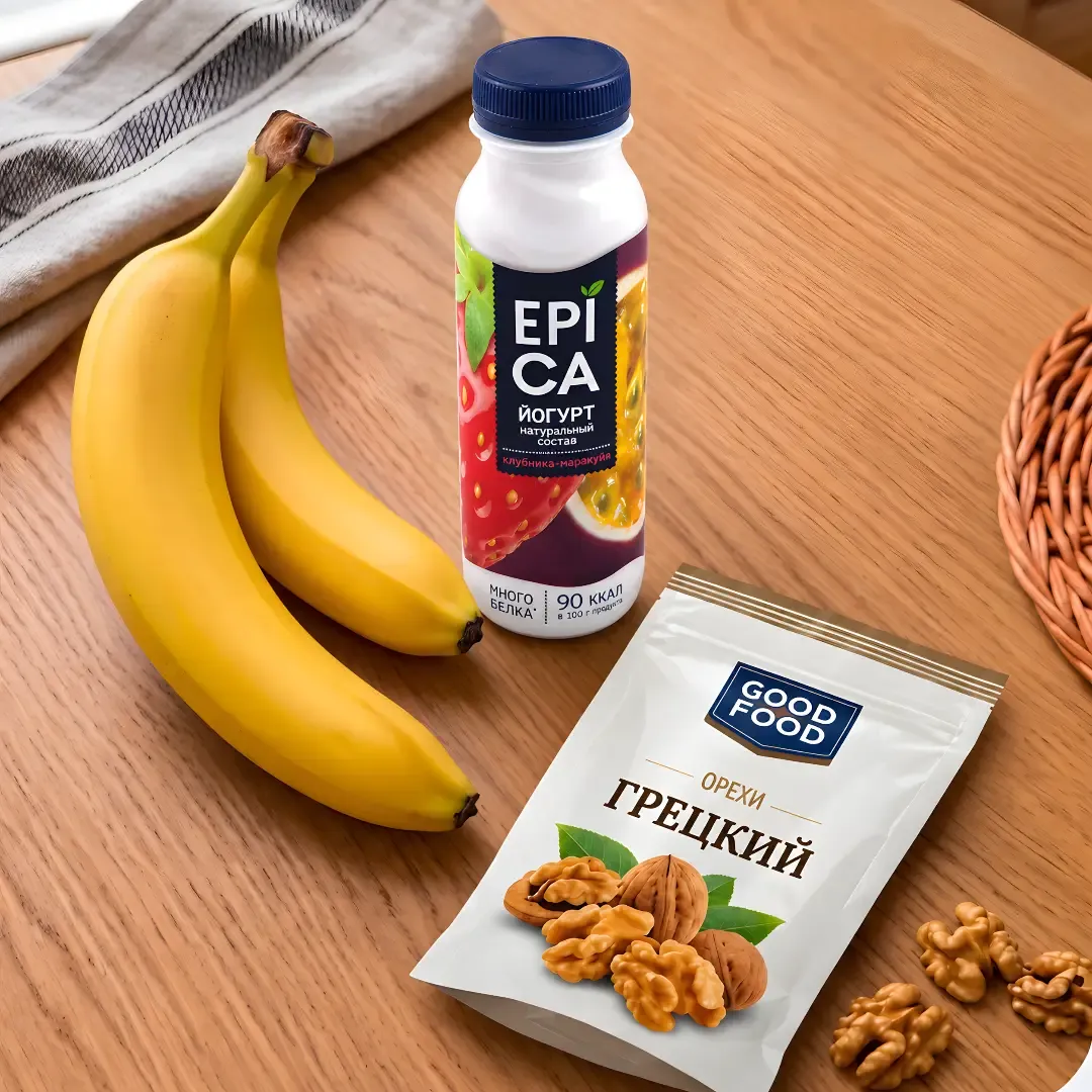 Bananas, yoghurt bottle, and walnuts package on a wooden table.