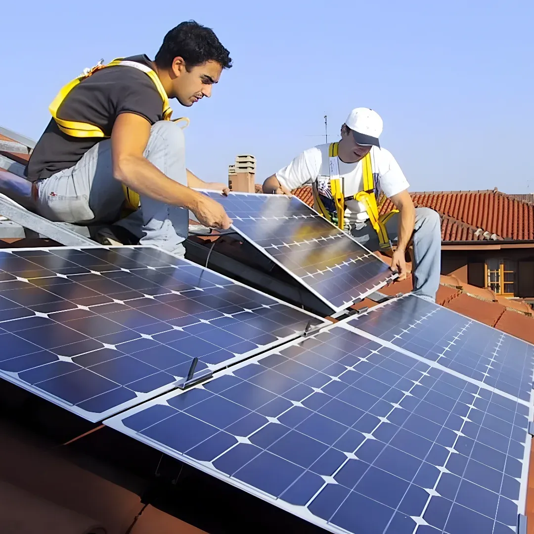 Two men installing solar panels on the roof of a building, surrounded by other buildings and a clear blue sky.