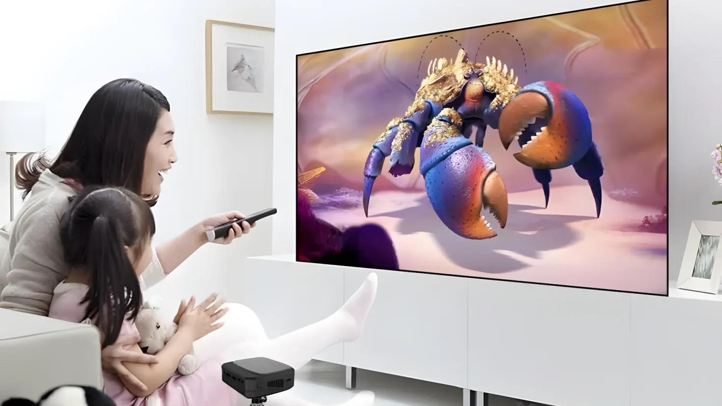 A woman sitting on a couch, holding a remote control in her hand and a teddy bear in her other hand. On the right side of the image, there is a television mounted on the wall, and on the left side, there are photo frames, a flower vase, and a lamp. In front of the television is an object on the floor, and in the background there are frames attached to the wall. This image is likely related to the new Samsung QLED TV, which has been launched in India.