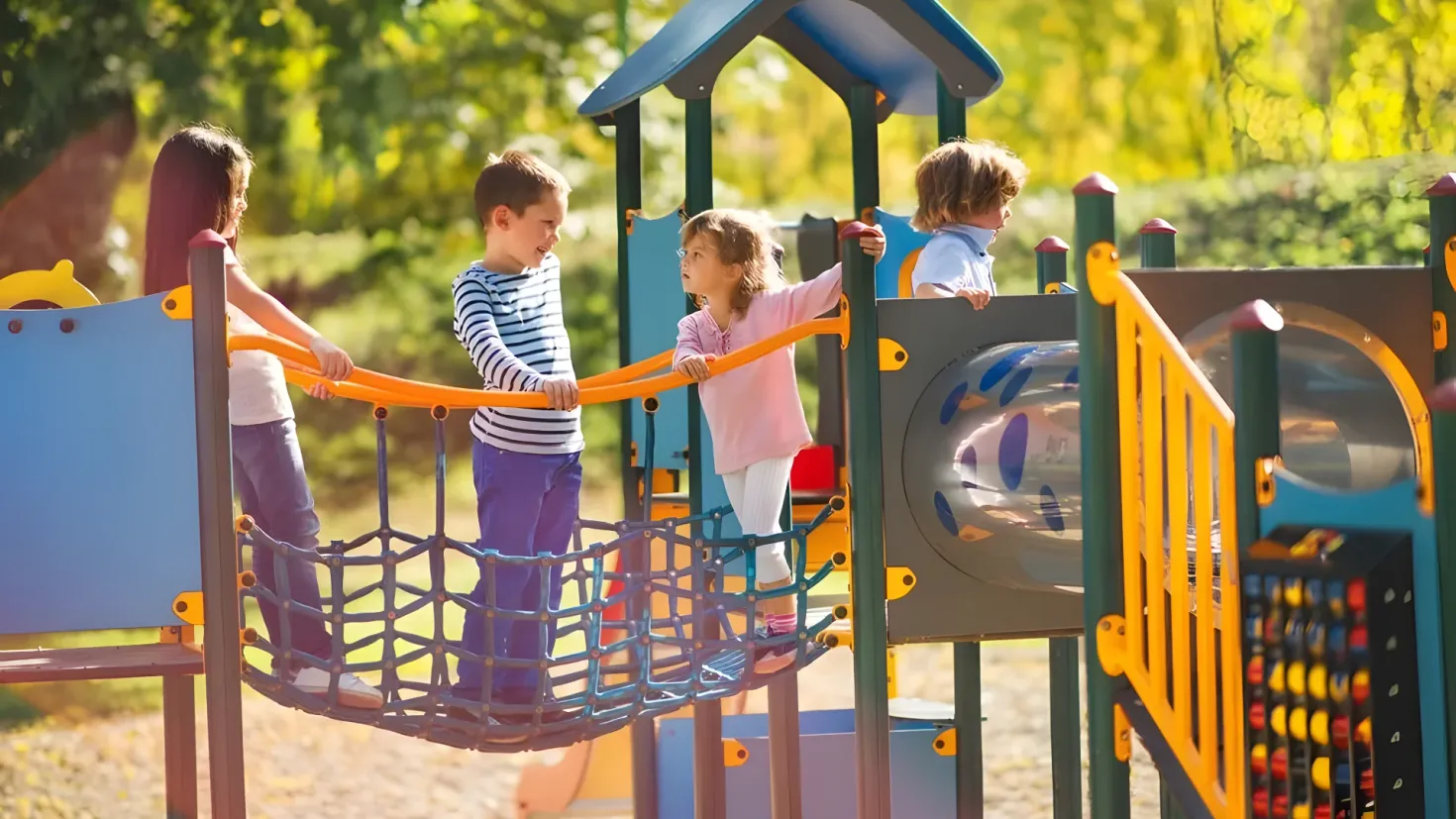A group of children playing on a playground in a park, surrounded by trees in the background. One of the children is wearing sneakers.