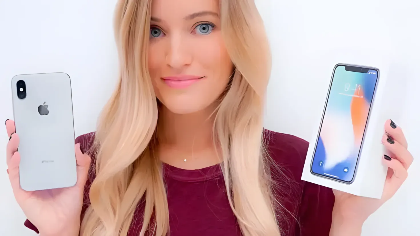 A woman holding up two iPhones in front of her face, with a white background. The phones appear to be the iPhone XS Max and XR, both of which are being reviewed.