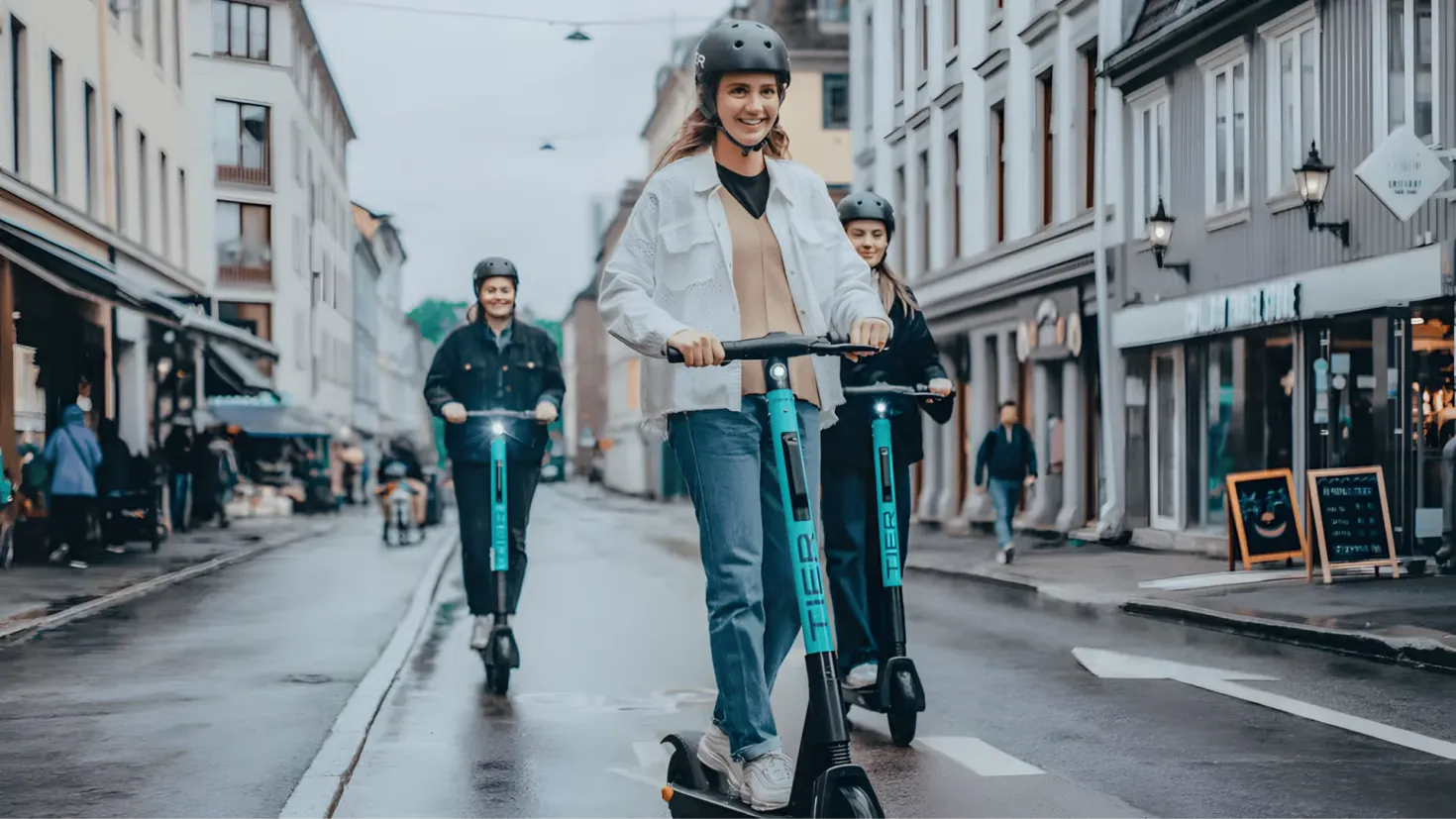 A group of people riding electric scooters down a street, wearing helmets and surrounded by buildings with windows, light poles, boards with text, and other objects. The sky is visible in the background.