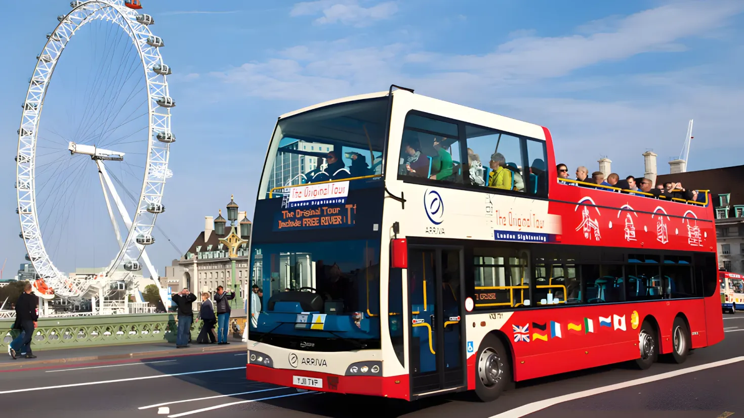 A red double decker bus driving down a street next to a giant ferris wheel. There are people inside the bus, and in the background there are buildings, trees, and a clear blue sky.